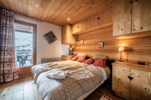 a bedroom with wooden walls and a bed with red pillows at Superbe Duplex- Résidence Alpine in Arâches-la-Frasse +37 photos