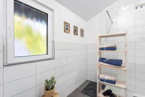 a bathroom with white tiled walls and a window at Ferienhaus 14 in Bad Arolsen +19 photos