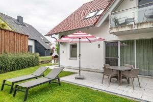 a patio with an umbrella and a table and chairs at Domizil Eden - Erdgeschoss in Göhren-Lebbin