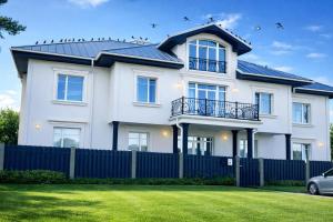 a white house with a blue fence at GRAND APARTMENT BALTEZERS in Riga