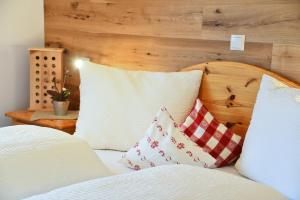 a bed with white pillows and a wooden headboard at Birkenhof - Wohnung Bichel in Sluderno