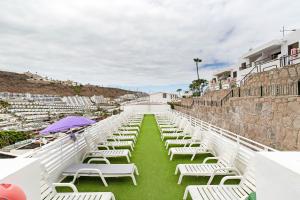 a row of white chairs sitting on the grass at Alohe Puertorico View in Puerto Rico de Gran Canaria