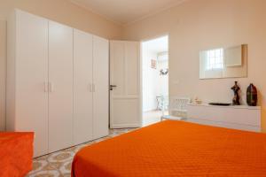 a bedroom with an orange bed and white cabinets at Leondoro - Pirandello in Santa Flavia