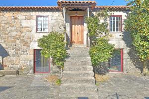 a stone house with stairs leading up to a wooden door at Casa De Vilar do Dão in Penalva do Castelo
