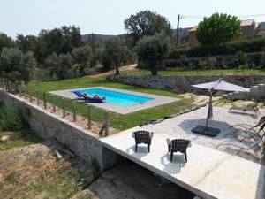 a swimming pool with two chairs and an umbrella at Casa De Vilar do Dão in Penalva do Castelo