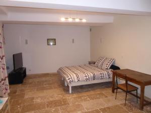 a bedroom with a bed and a table and a desk at Maison de Village in Puimoisson
