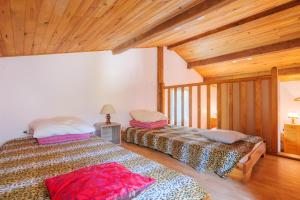 two beds in a room with wooden ceilings at Gite de la Troulière in Banne