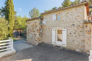 a stone house with a white door and a fence at Gite de la Troulière in Banne