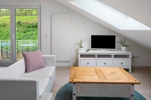 a living room with a white couch and a tv at Ferienhaus Engelsberghof in Endingen