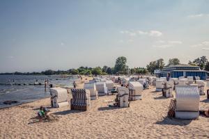 a beach with chairs and a child sitting on the beach at Ferienhaus Haffstille in Ueckermünde