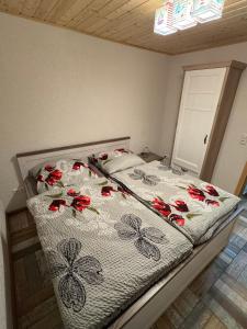 a bed with red flowers on it in a bedroom at Ferienhaus Haffstille in Ueckermünde