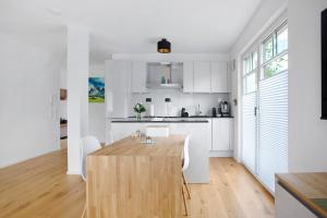 a kitchen with white cabinets and a wooden table at Design Ferienwohnung am Chiemsee in Breitbrunn am Chiemsee