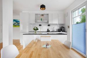a kitchen with white cabinets and a wooden floor at Design Ferienwohnung am Chiemsee in Breitbrunn am Chiemsee +14 photos