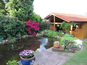 a pond in front of a house with flowers at Ferienwohnung Lortz in Cuxhaven