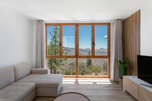 a living room with a couch and a large window at Los Mojones in Artenara