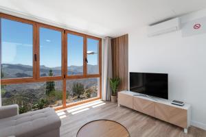 a living room with a large window and a flat screen tv at Los Mojones in Artenara
