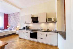 a kitchen with white cabinets and a living room at Englisches Apartment in Kerken +14 photos