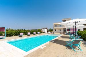 a swimming pool with chairs and umbrellas next to a building at Le scuderie 5 in Galatone