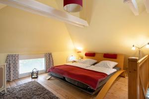 a bedroom with a bed with a red blanket and a window at Haus am alten Deich in Rodenäs