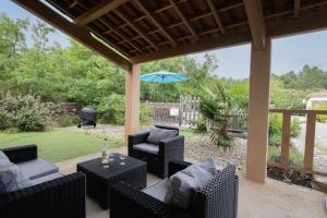 an outdoor patio with chairs and an umbrella at Villa La Fenière in Payzac