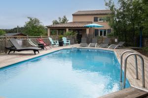 a large swimming pool with chairs and a house at Villa La Fenière in Payzac