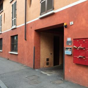 um edifício laranja com uma porta vermelha ao lado de uma rua em Ampio monolocale em Brescia
