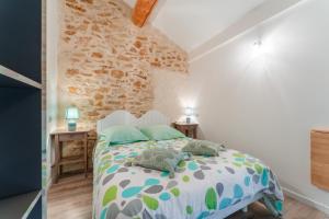 a bedroom with a bed and a stone wall at Chambre Olive Verte in Piolenc