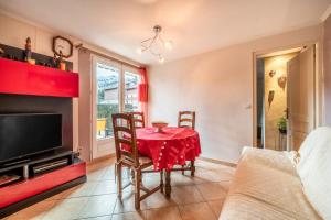 a living room with a red table and chairs and a tv at Appartement Bernex - 3 personnes in Bernex