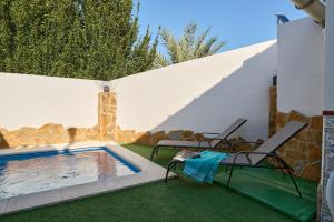a swimming pool in a yard with two chairs and a table at Casa Ángeles in Cuevas Bajas