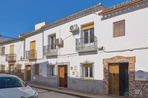 a white building with a car parked in front of it at Casa Ángeles in Cuevas Bajas