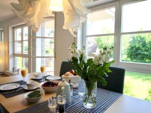 a dining room table with a vase of flowers on it at Komfort-Ferienwohnung am See in Bodman-Ludwigshafen