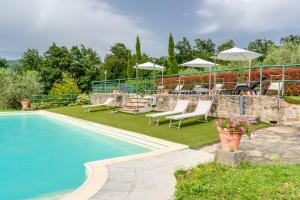 a swimming pool in a yard with chairs and umbrellas at Il Cerro Appartamento Basic per due in Pelago