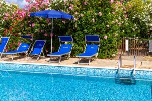 a group of chairs and an umbrella next to a swimming pool at Bilo Hedera in Marina di Grosseto