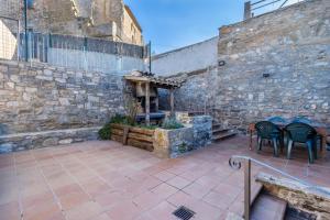 a patio with tables and chairs and a stone wall at Casabras Rural in Claravalls