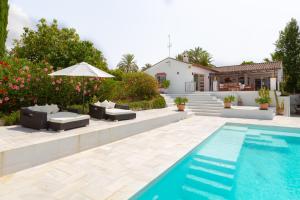 a pool with chairs and an umbrella next to a house at Almijan Alegria in Estepona