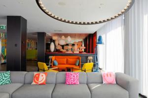 a living room with a gray couch with colorful pillows at citizenM Glasgow in Glasgow +29 photos
