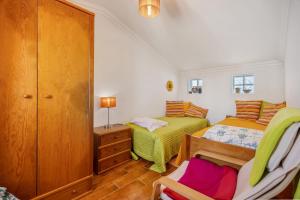 a bedroom with two beds and a chair in it at Burgau - A Casa dos Avós in Burgau