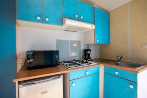 a small kitchen with blue cabinets and a microwave at Mobil home 2 Bikini in Plouha