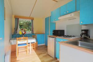 a kitchen with blue cabinets and a table and a sink at Mobil home 2 Bikini in Plouha