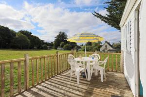 a table and chairs on a deck with an umbrella at Mobil home 2 Bikini in Plouha +12 photos