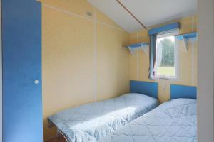 two beds in a small room with a window at Mobil home 2 Bikini in Plouha
