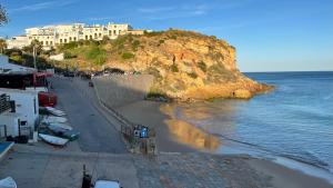 a beach with buildings on a hill next to the water at Burgau - A Casa dos Avós in Burgau