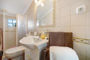 a bathroom with a sink and a toilet and a mirror at Burgau - A Casa dos Avós in Burgau