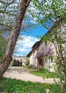an old stone barn with purple flowers on it at Chambre d'hôte in Meymac
