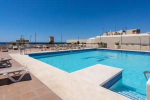 a large swimming pool with chairs at Apartment with Swimming-pool in Marbella