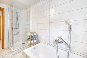 a white bathroom with a tub and a shower at Fewo Allezeit Sauerland in Drolshagen +35 photos