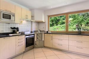 a kitchen with white cabinets and a large window at Apartment Bodnerhof in Nova Ponente