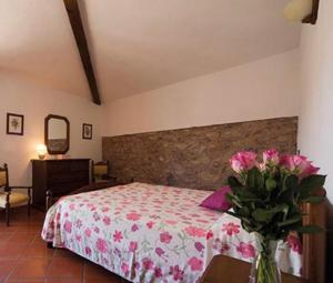 a bedroom with a bed with a vase of pink flowers at Agriturismo Il Colletto in Albenga