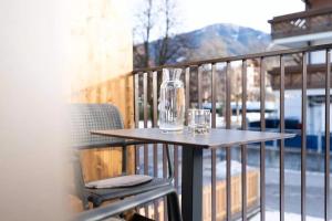 a table with two glasses and a bottle on a balcony at App Kronplatz Villa Colli in Valdaora