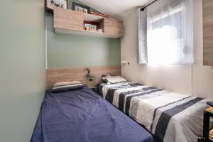 two beds in a room with a window at Mobilhome - Piscine - Premium in Erdeven